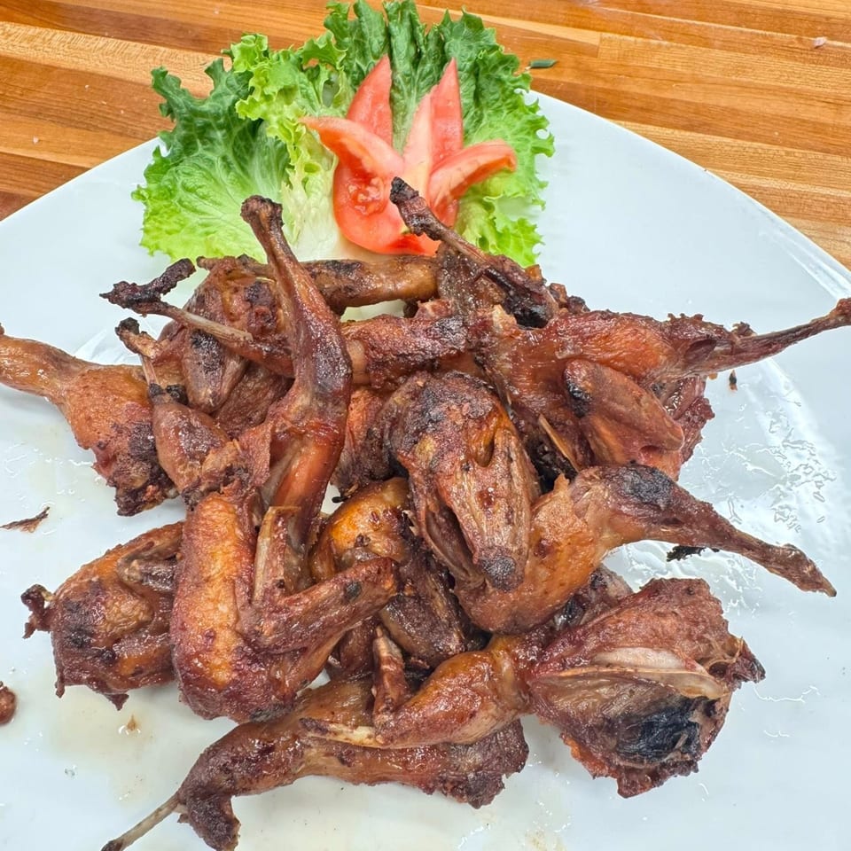 Platter of crispy fried quail, garnished with fresh lettuce and a carved tomato flower.